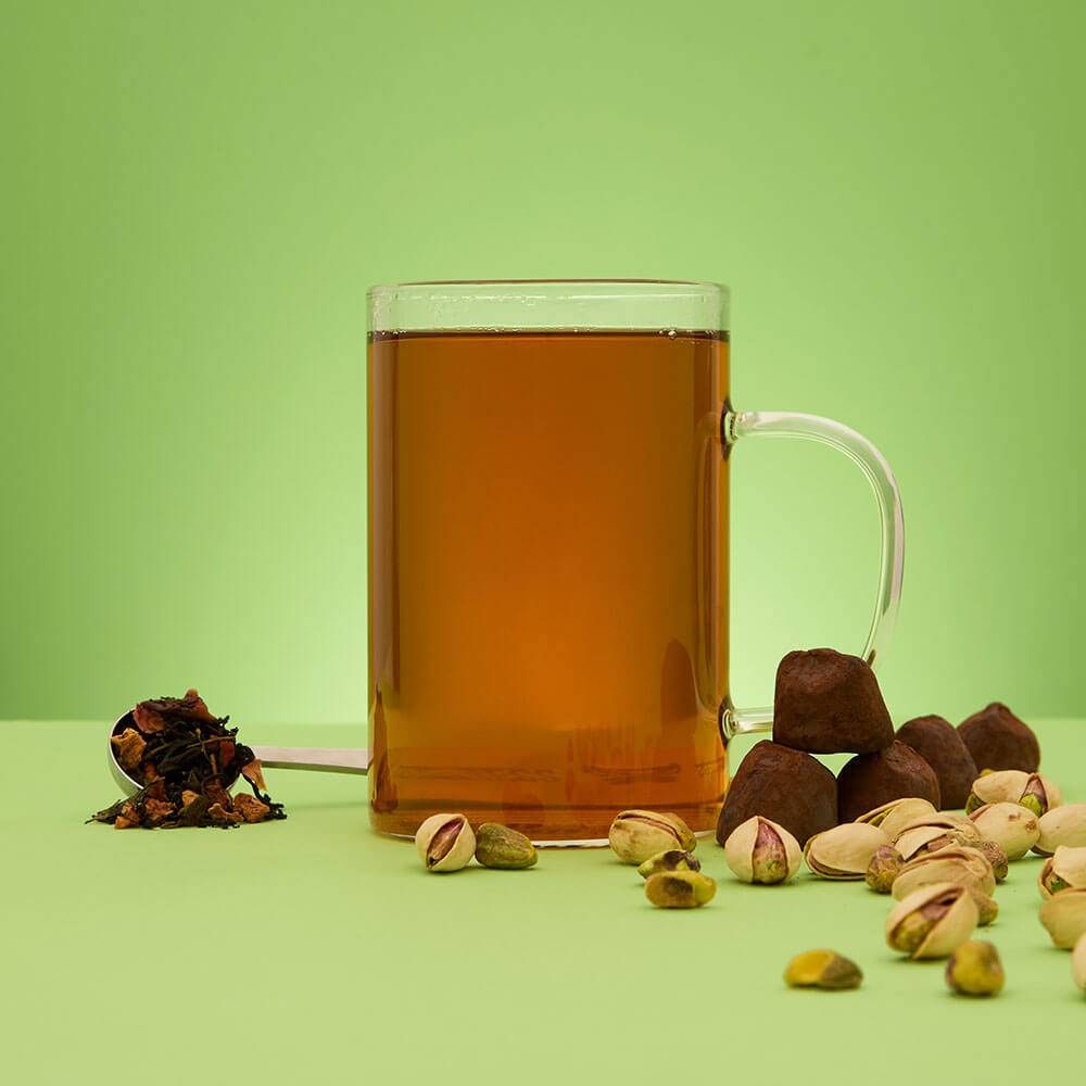 hot pistachio chocolate truffle tea with loose leaf tea in a spoon and pistachio and chocolate truffles