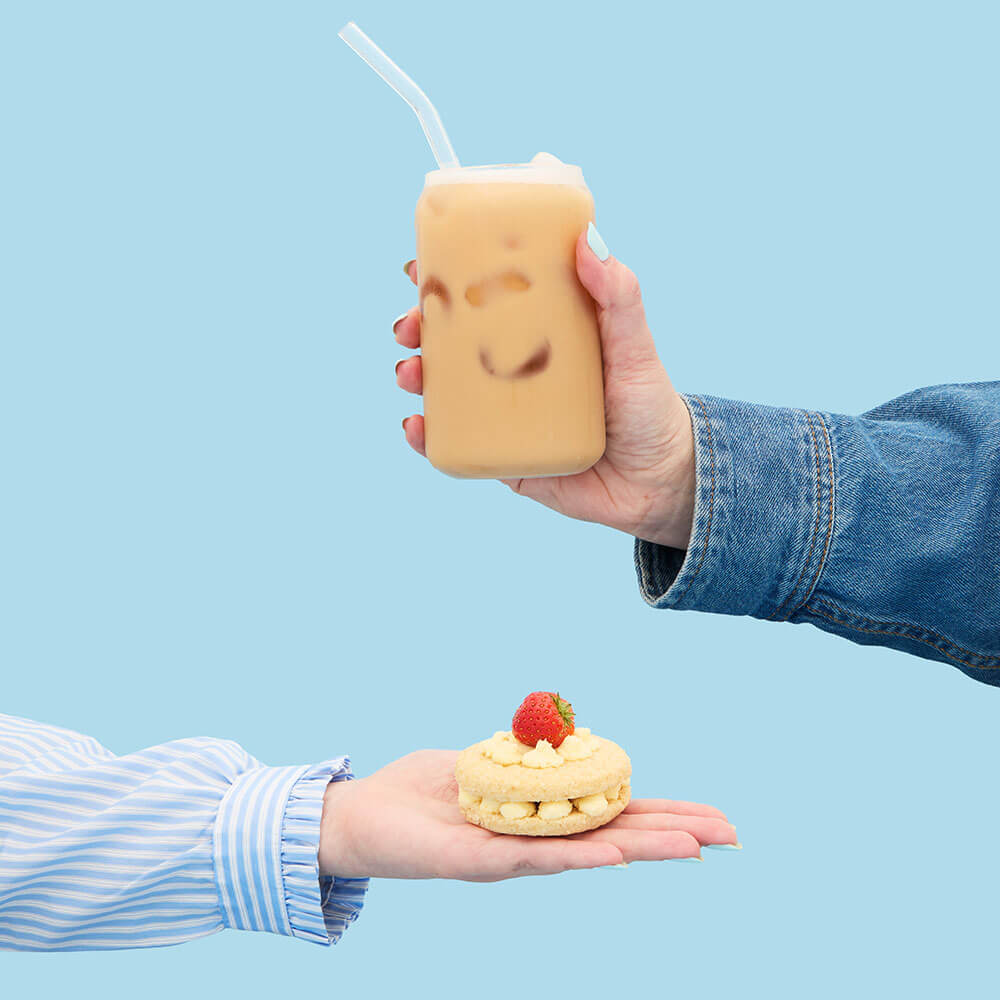 hand holding strawberry shortcake biscuit and strawberry shortcake biscuit iced tea latte