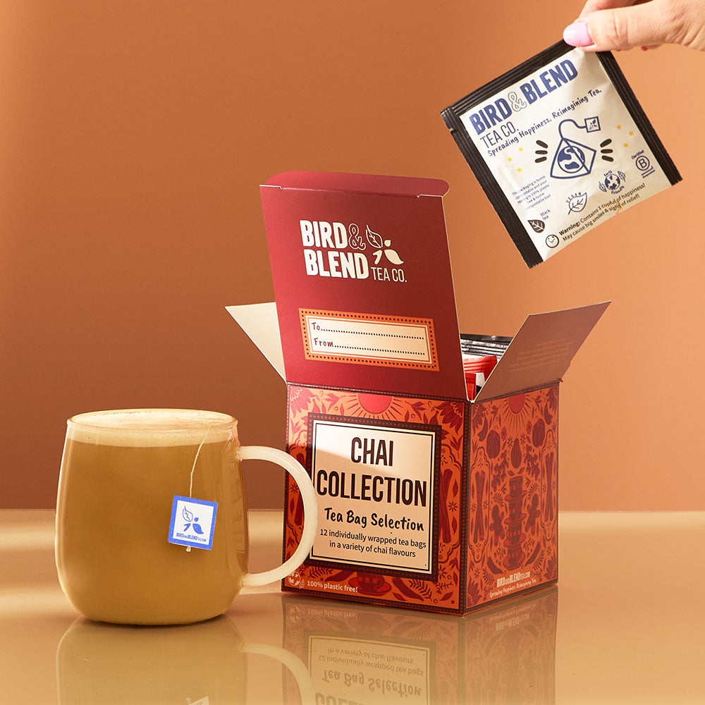 hot chai latte with tea bag in it &amp; chai tea bag gift cube open filled with individually wrapped tea bags &amp; person pulling tea bag out