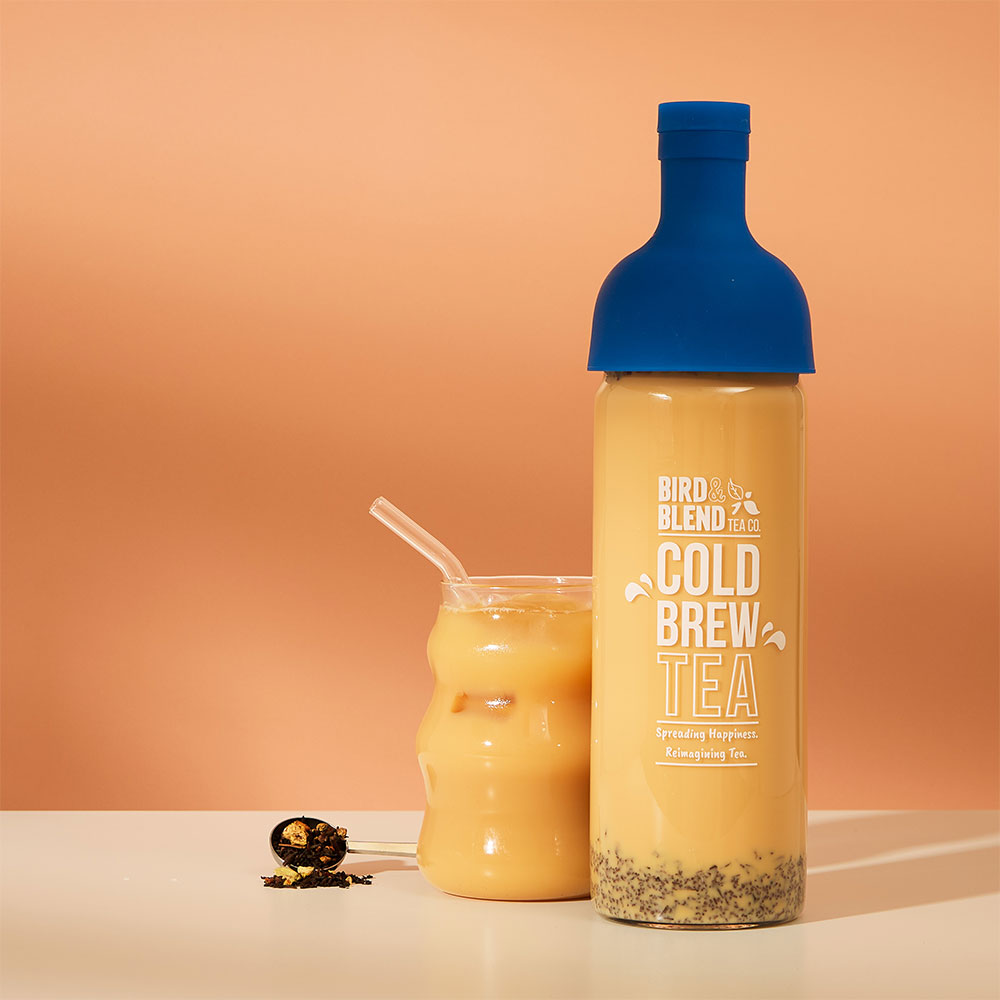 iced maple apple chai latte & perfect tea spoon filled with loose leaf tea with a sapphire blue cold brew tea bottle filled with tea with milk