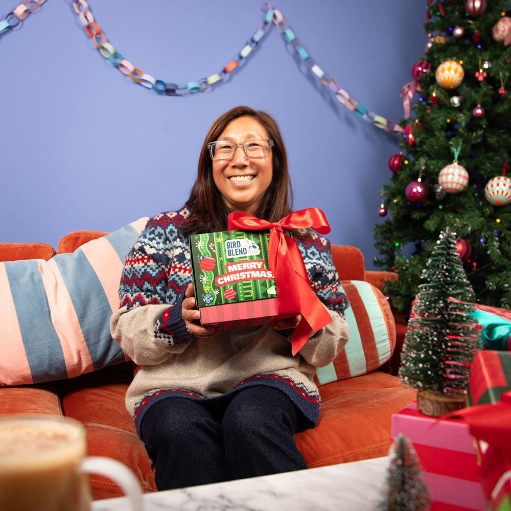 person holding closed christmas tea bag selection box wrapped in a big red bow