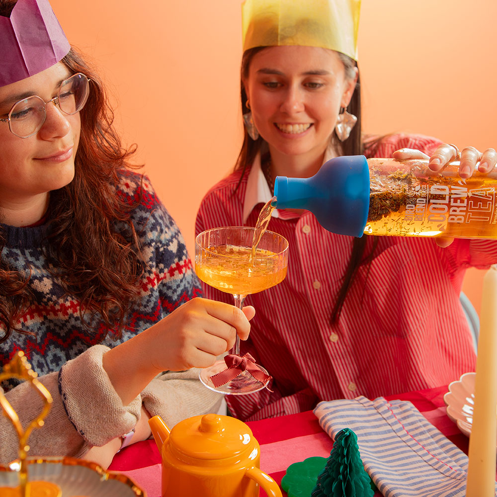 person pouring limoncello from a sapphire blue cold brew tea bottle into glass